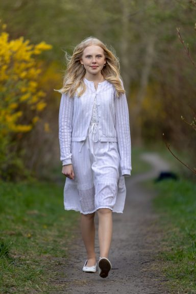 Konfirmand går i tunnel av blommande forsythia i Bjärred, familje- och porträttfotograf Anna Esmelöv