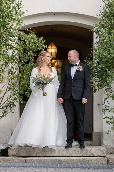 Brudpar skrattar glatt som nygifta på Kuddby kyrkas kyrktrappa, bröllopsinspiration och foto av Anna Esmelöv