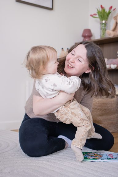 Lifestyle fotografering där mamma leker och busar med sitt barn på golvet, foto av Anna Esmelöv