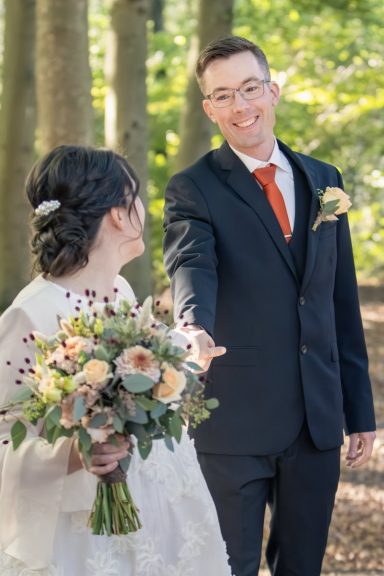 Bruden drar lekfullt med sig brudgummen i en vacker ljus skog, bröllopsfotografering med naturligt ljus, Anna Esmelöv