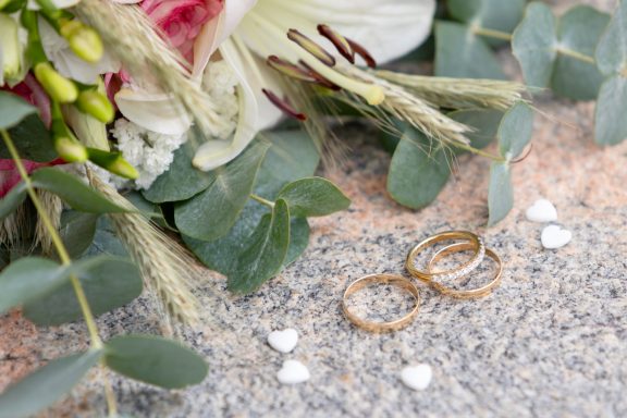 Detaljbild av brudbukett, hjärtformad konfetti och vigselringar på stentrappa, fotograferat av Anna Esmelöv