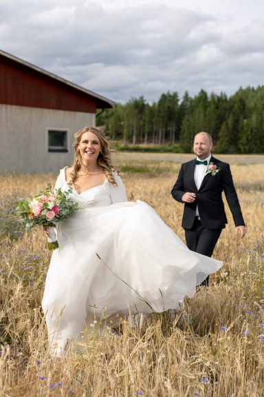 Brudpar jagar varandra lekfullt på en åker i Kuddby utanför Söderköping, fotograferat av bröllopsfotograf Anna Esmelöv
