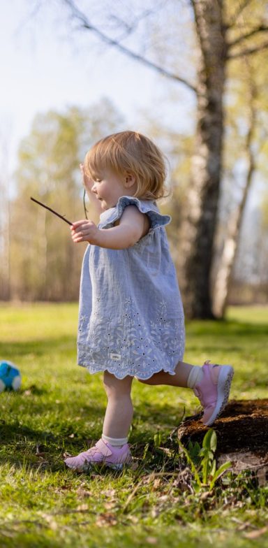 Barn leker i trädgård med pinne efter dop i Mantorp, familjefotograf Anna Esmelöv